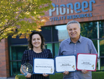 Victoria and Leon hold awards in front of Pioneer's office.